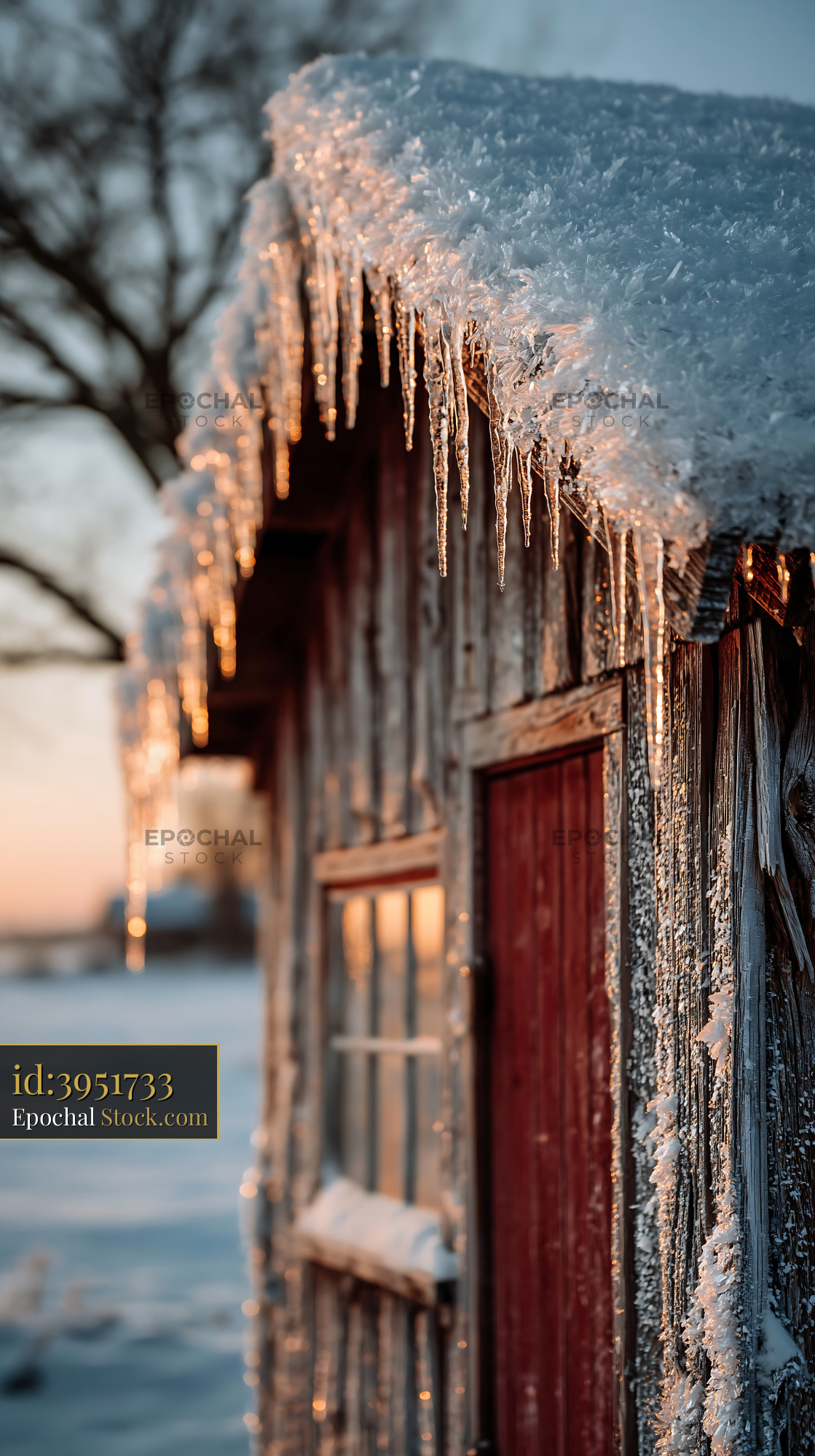 Icicles hanging from a snow covered empty cabin at sunset - stock photo