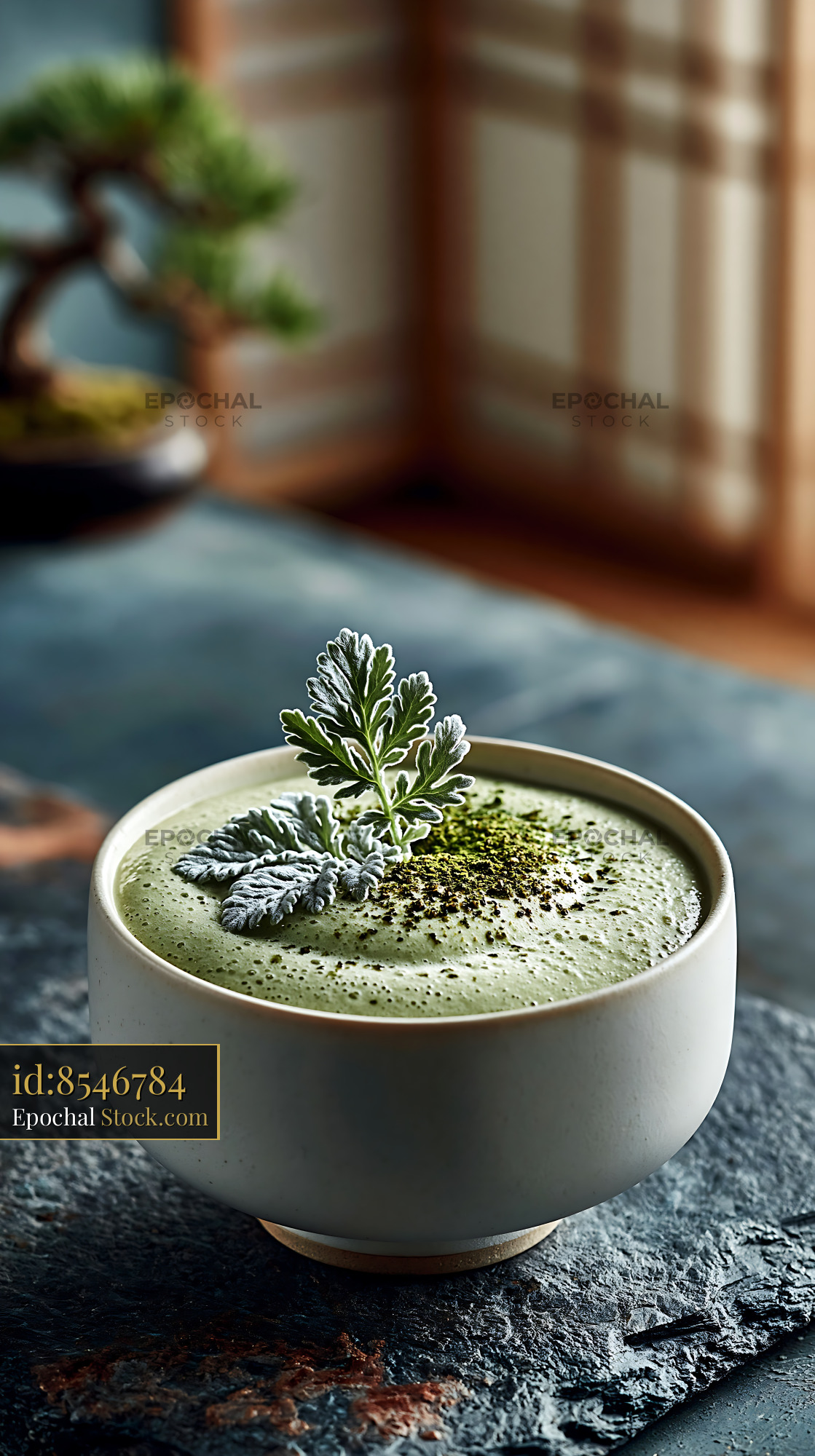 Green mugwort herb smoothie in a ceramic bowl with bonsai background - stock photo