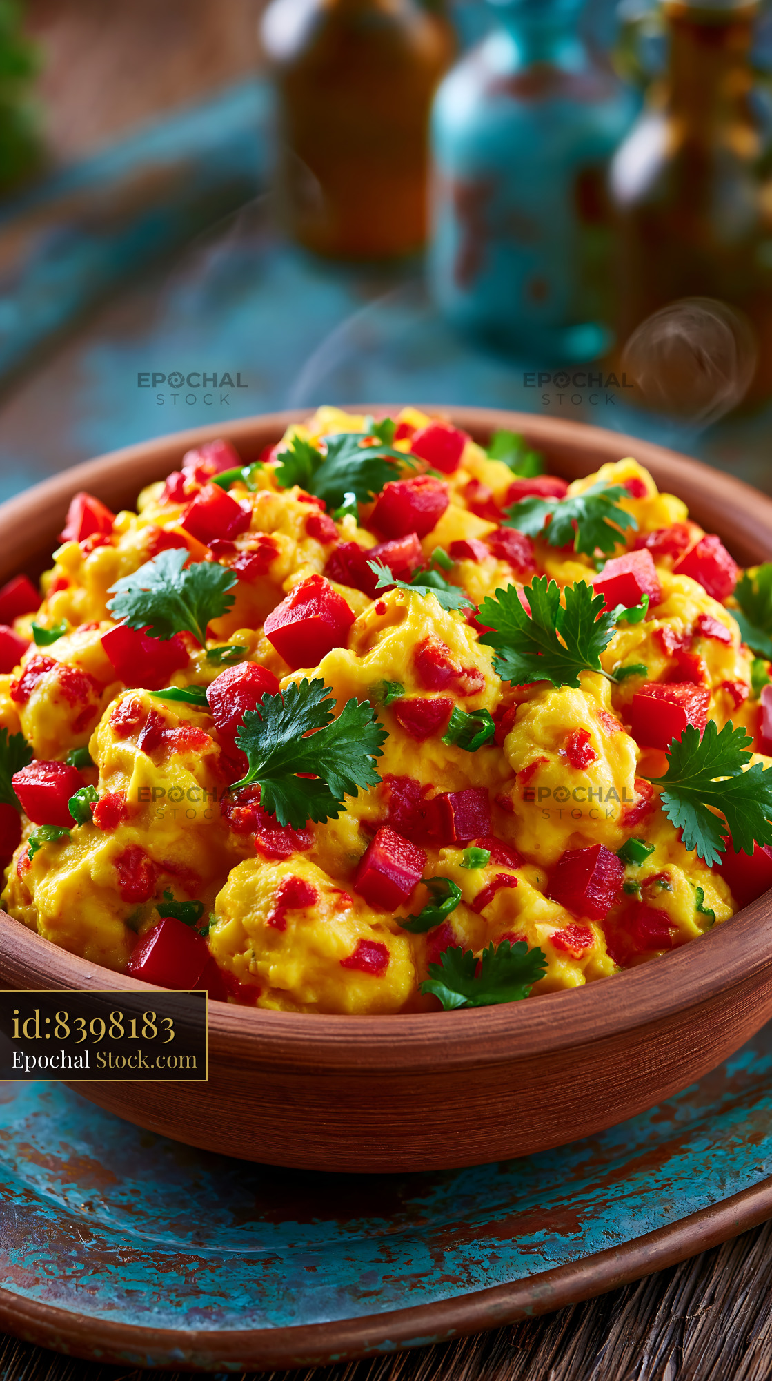 Fresh scrambled eggs with red bell pepper and cilantro in clay bowl - stock photo