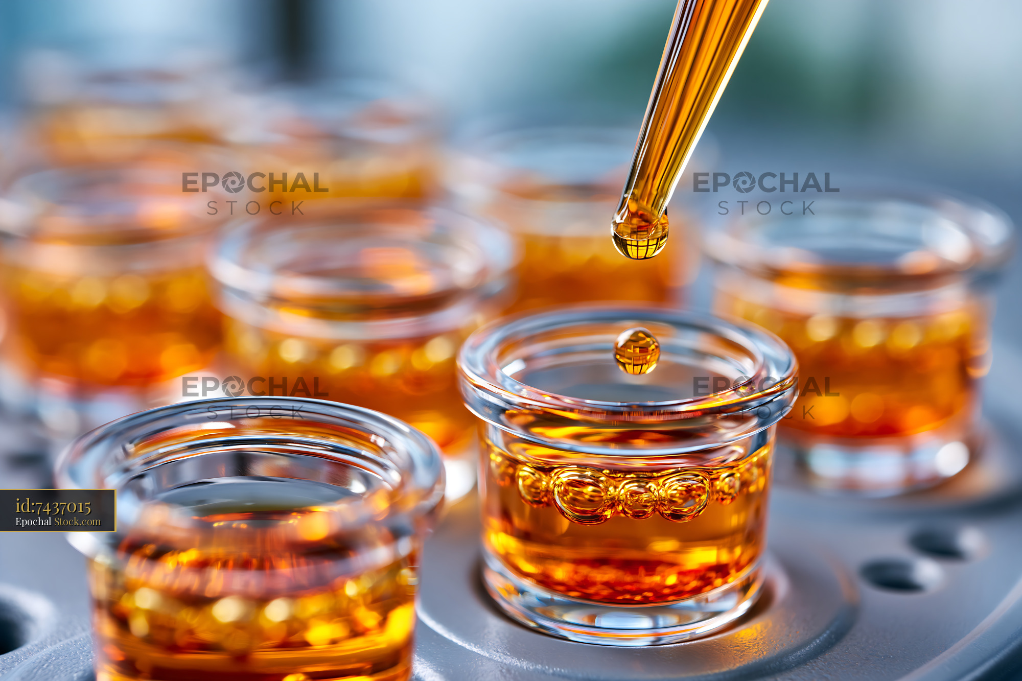 Pipette dripping golden liquid into small vial for diagnostic assay - stock photo
