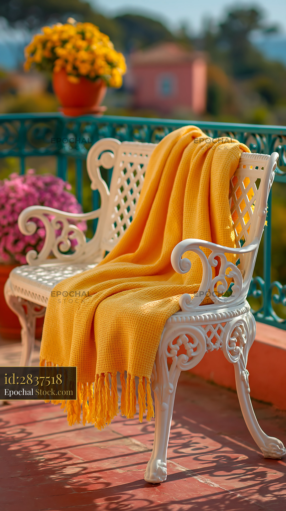 White ornate balcony bench with yellow throw blanket in the sun - stock photo