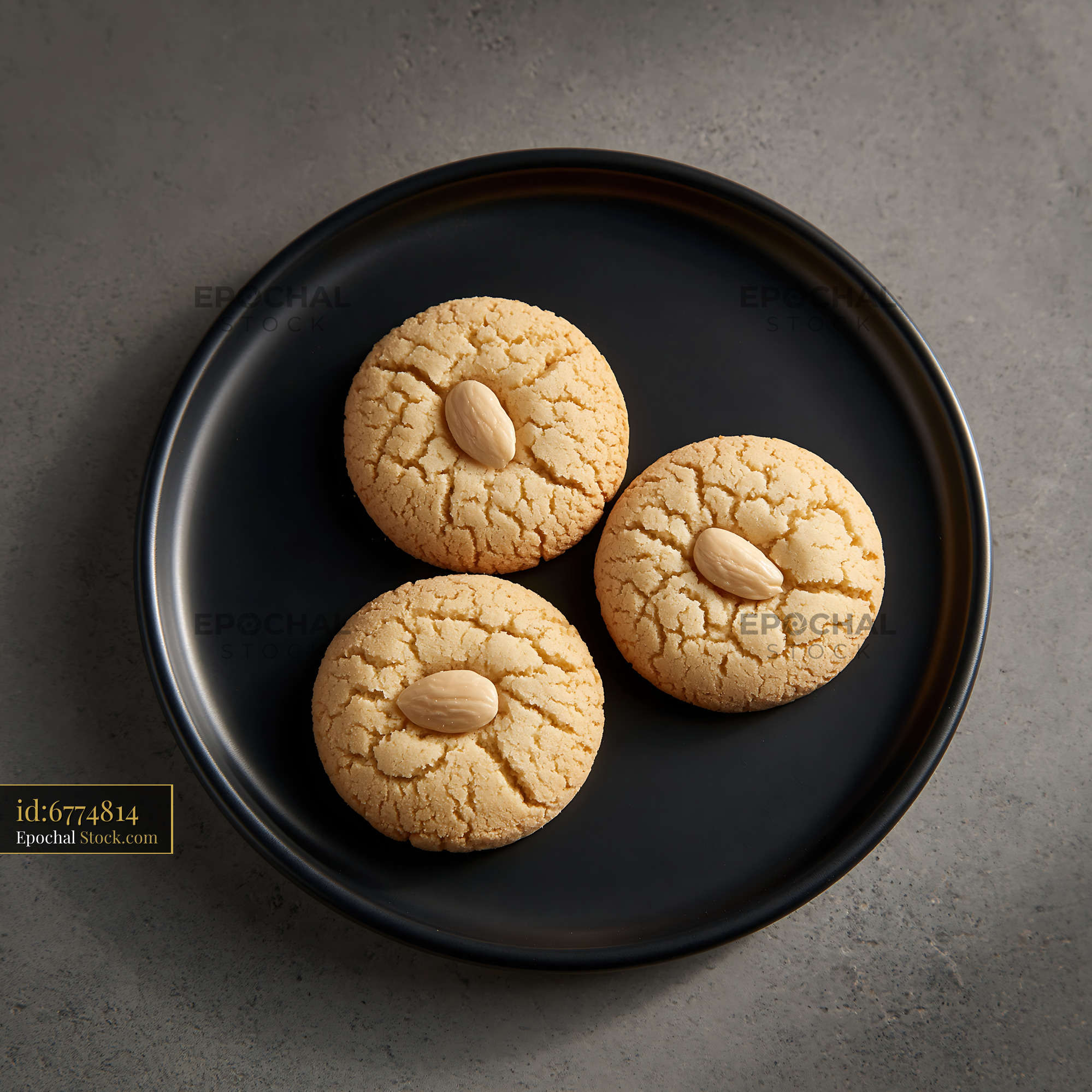 Three traditional acibadem kurabiyesi almond biscuits on a black plate - stock photo