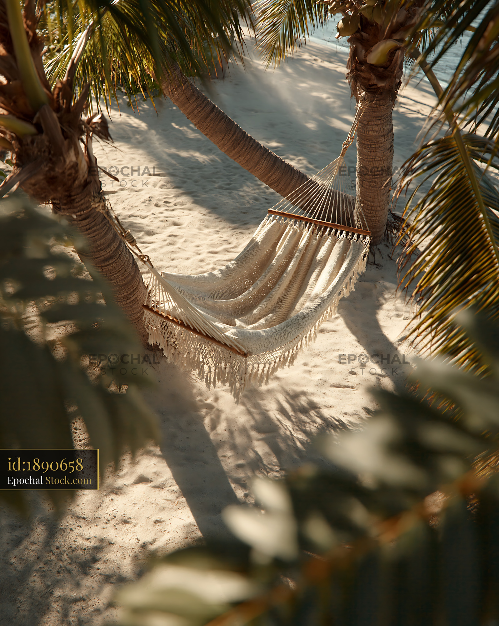 Woven hammock between palm trees on a sunny sandy beach - stock photo