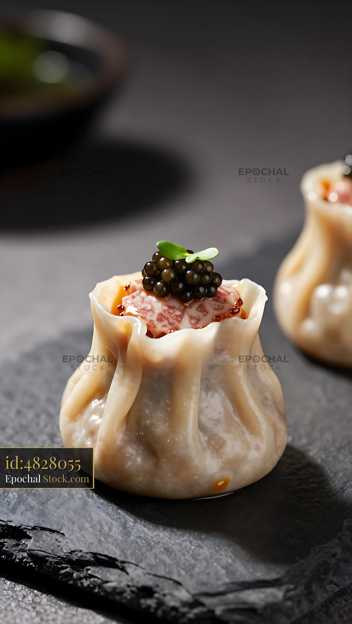 Wagyu shumai dumpling topped with black caviar on a slate plate - stock photo