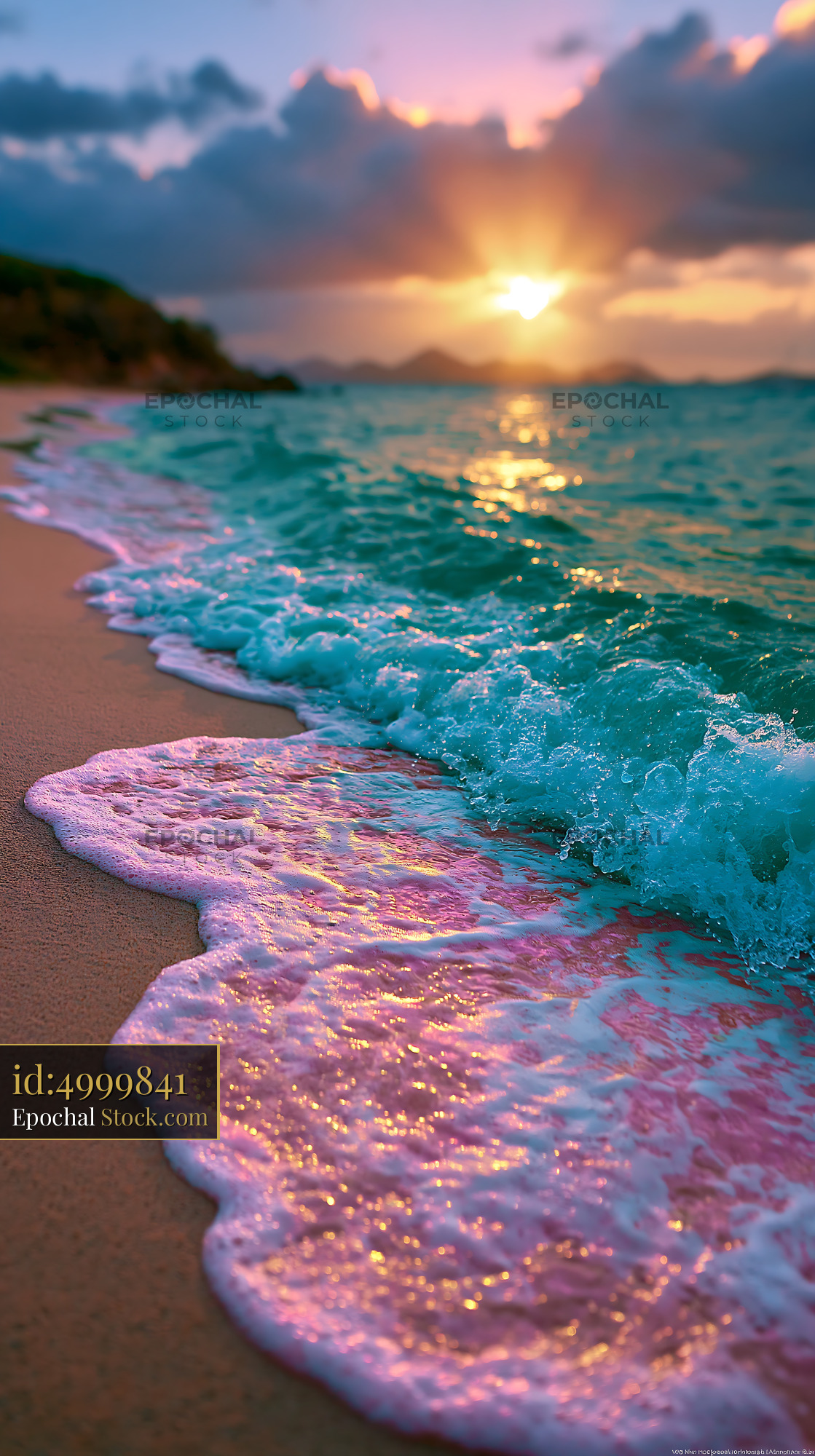Turquoise ocean wave with pink foam on a sandy beach at sunset - stock photo