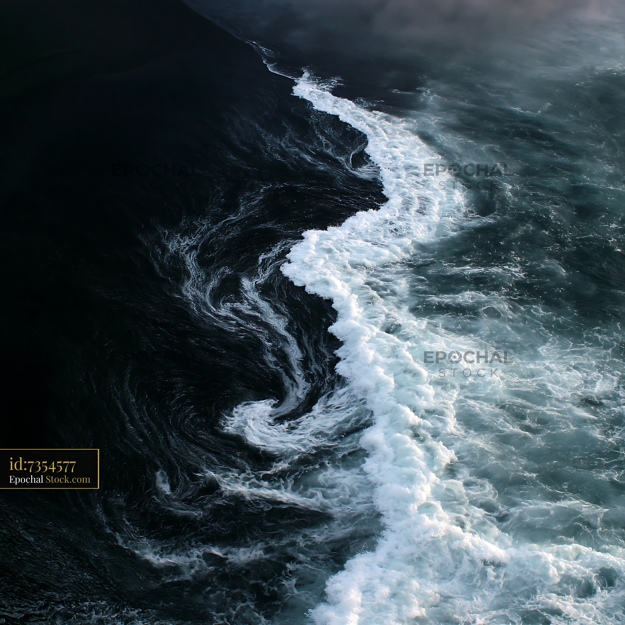 Aerial view of white sea foam swirling on a black sand beach - stock photo