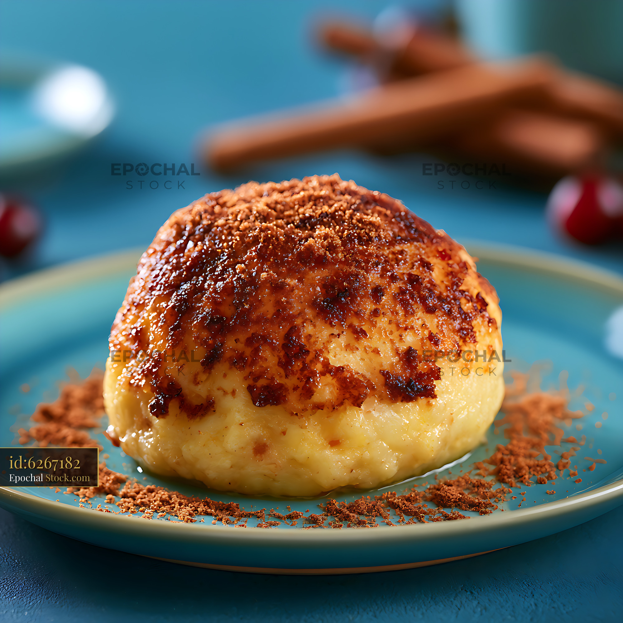 Sweet dumpling with caramelized cinnamon crust on a teal plate - stock photo