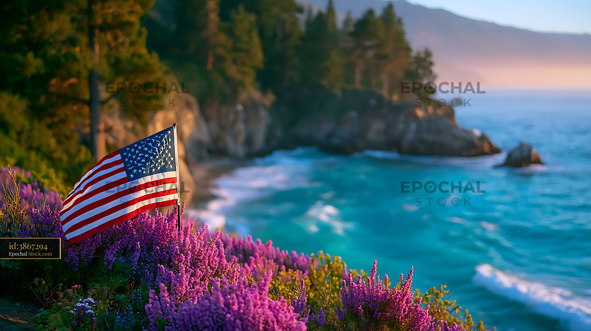 American flag on Big Sur coastline with purple wildflowers at sunset - stock photo
