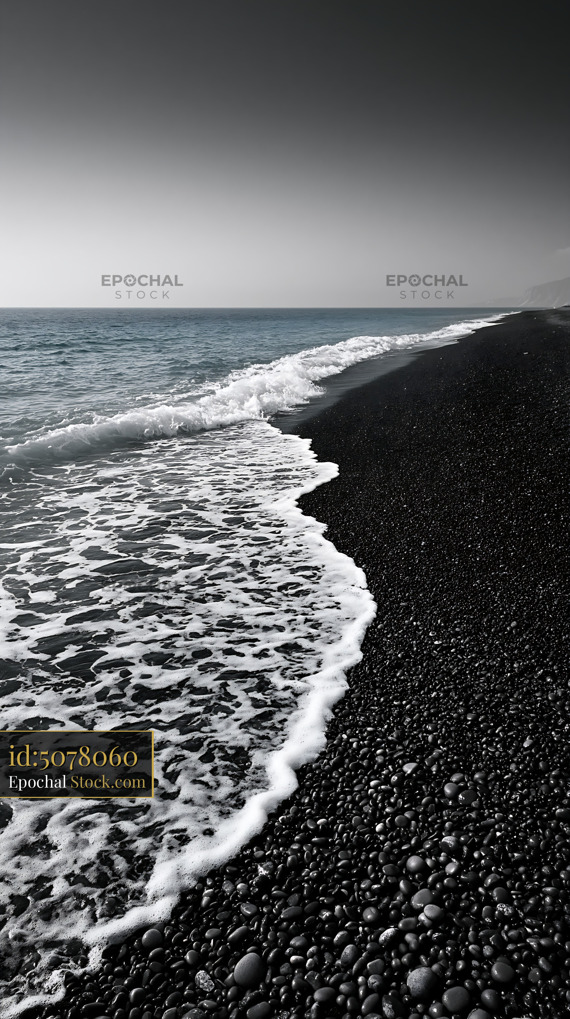 White sea foam washing over a black pebble beach at the coast - stock photo
