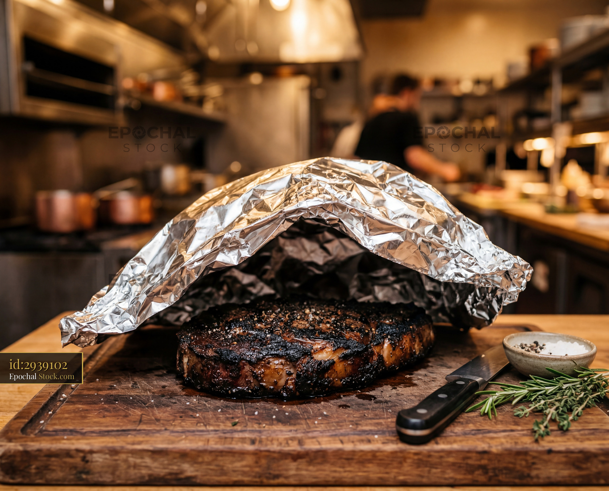 Seared Steak Resting Under Foil in Chef Kitchen - stock photo