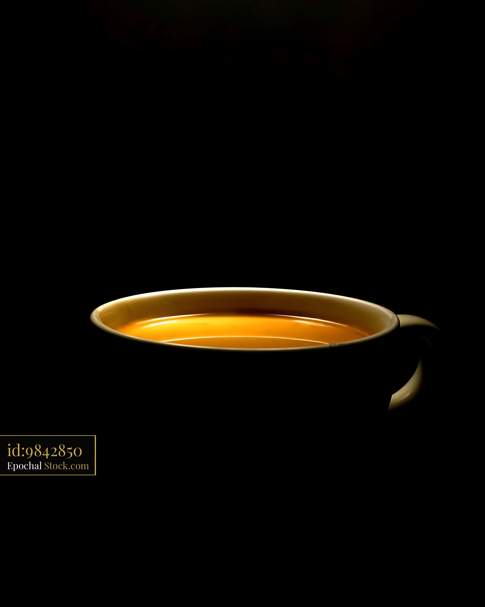 Golden Tea in Ceramic Cup Against Black - stock photo