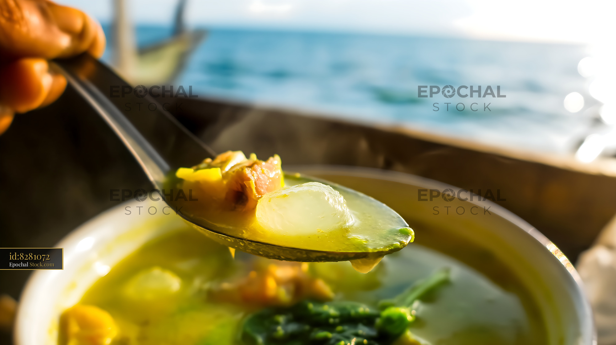 Steaming Kapurung Soup Spoon with Ocean Backdrop - stock photo