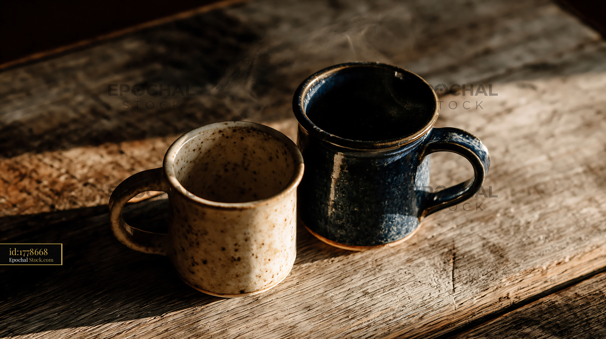 Two steaming ceramic mugs on rustic wooden table in morning sunlight - stock photo