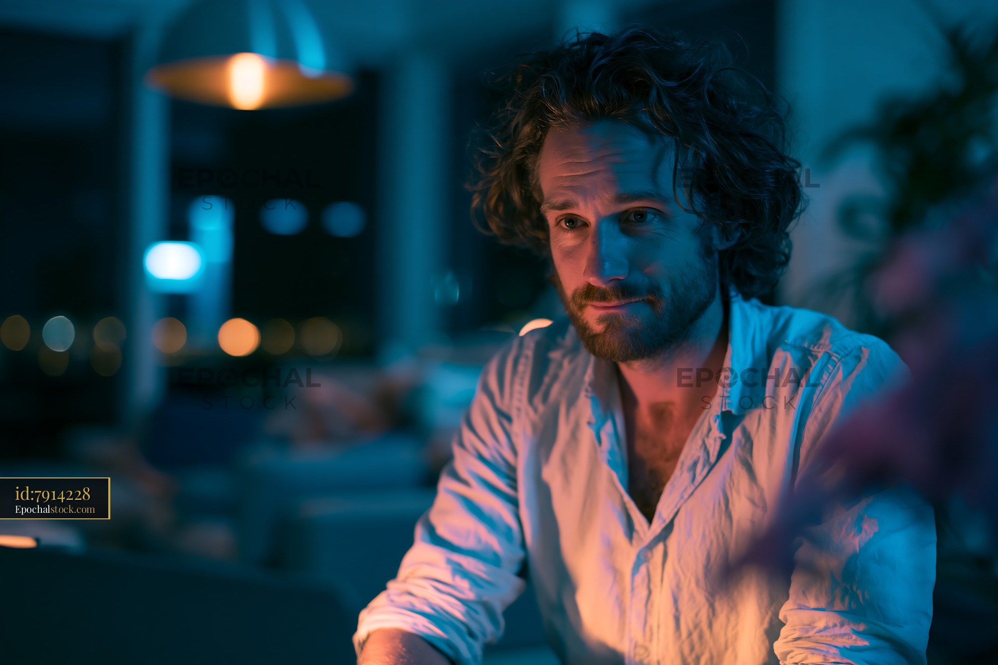 Watermarked full-resolution preview of Man sitting and looking thoughtfully in a dimly lit room