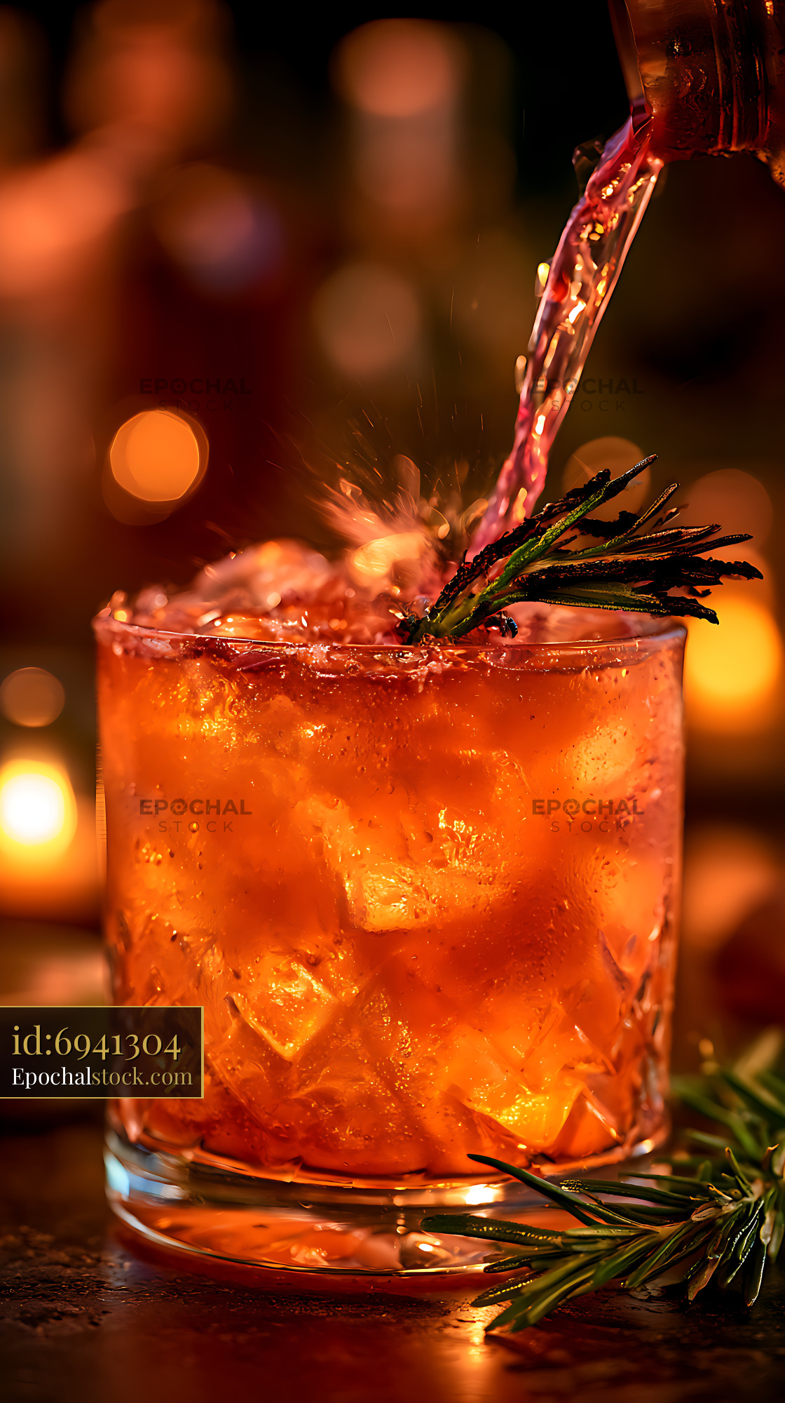 Watermarked full-resolution preview of Refreshing orange drink with ice and rosemary in warm light