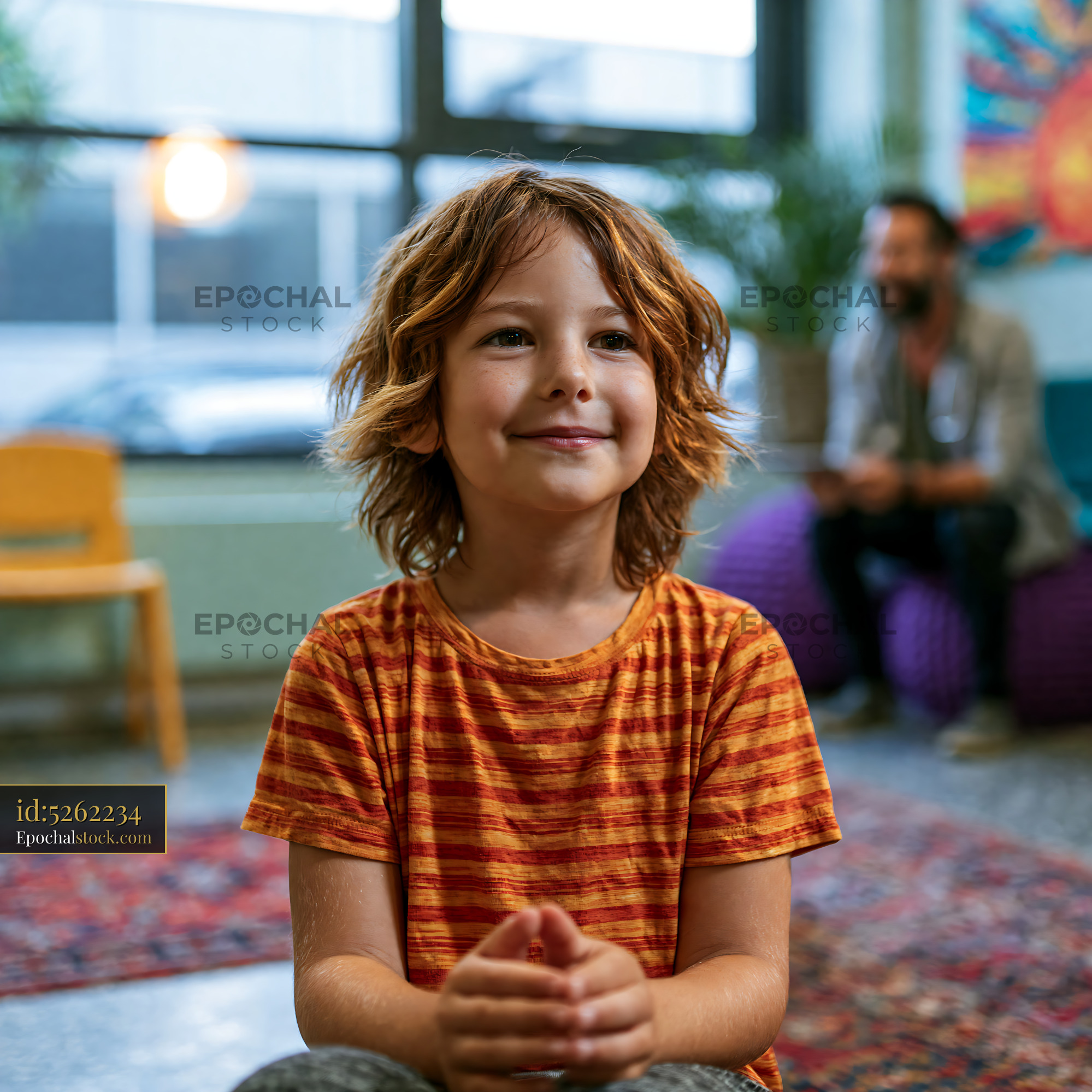 Watermarked full-resolution preview of Boy sitting in a colorful room with a smile on his face