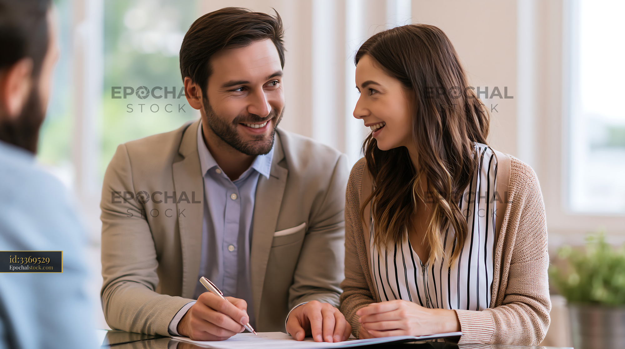 Watermarked full-resolution preview of Couple discussing plans in a bright office setting