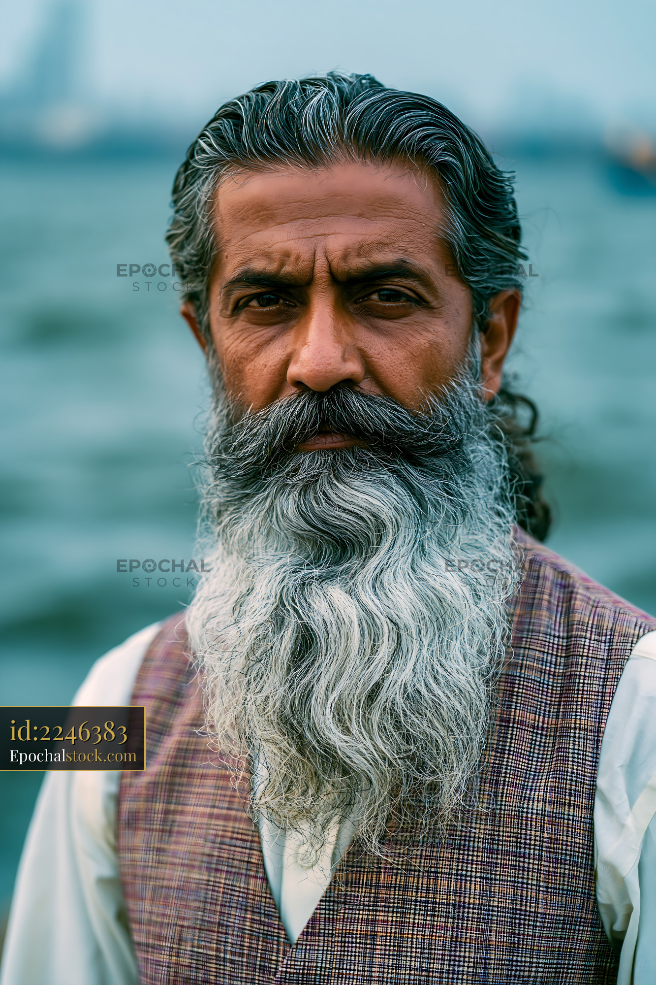 Man With Long Beard Standing by Water With a Serious Expression - stock photo