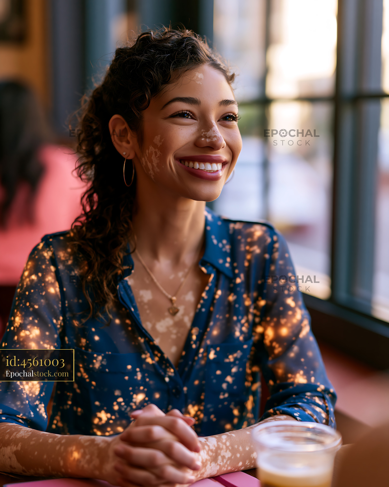 Watermarked full-resolution preview of Woman smiling while sitting at a cafe table in the city
