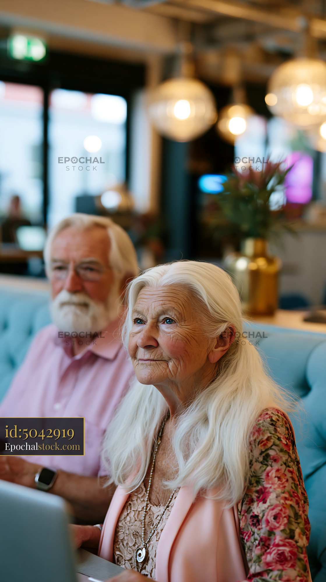 Elderly Couple Working Together in a Modern Cafe Setting - stock photo