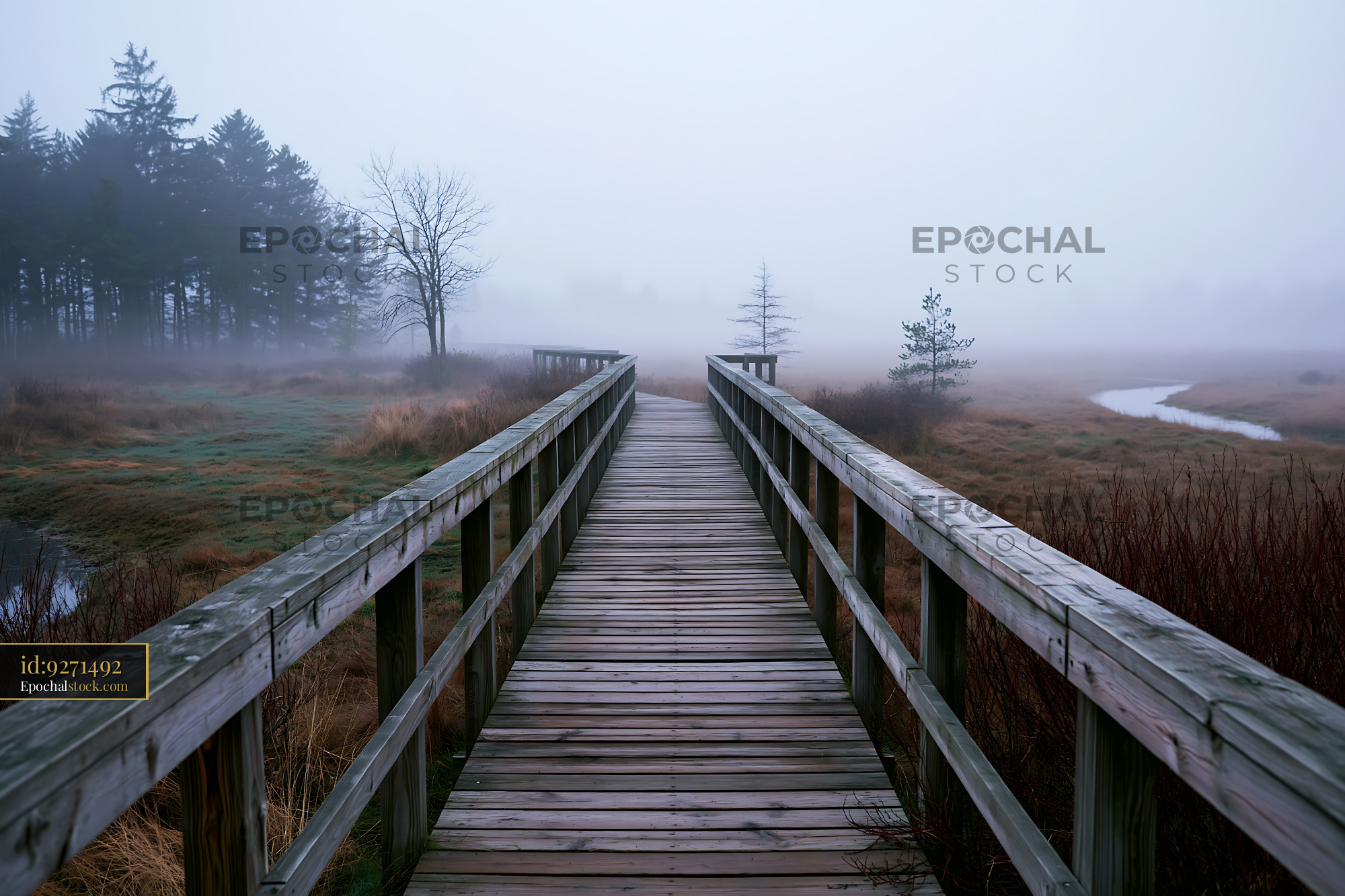 Fog drifting across meadow with wooden pathway leading into distance - stock photo