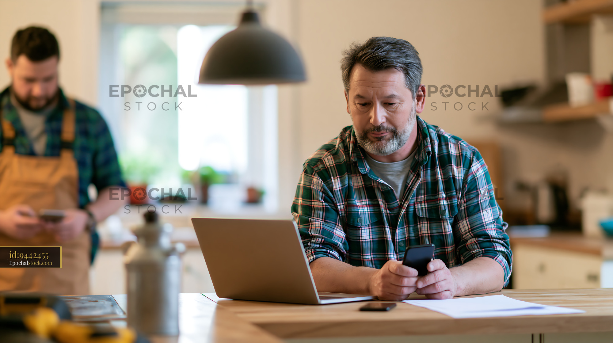 Watermarked full-resolution preview of Men using devices in a kitchen workspace
