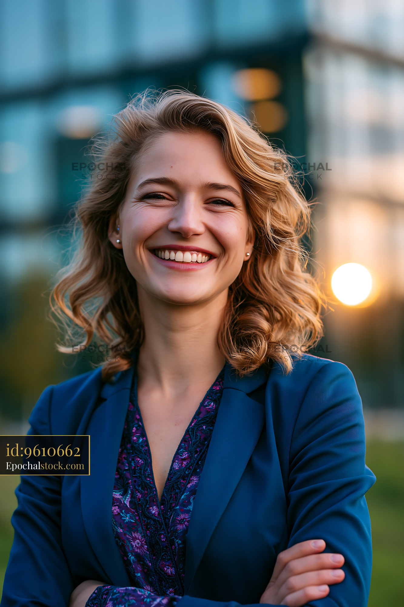 Watermarked full-resolution preview of Smiling woman in a blue blazer against urban sunset backdrop