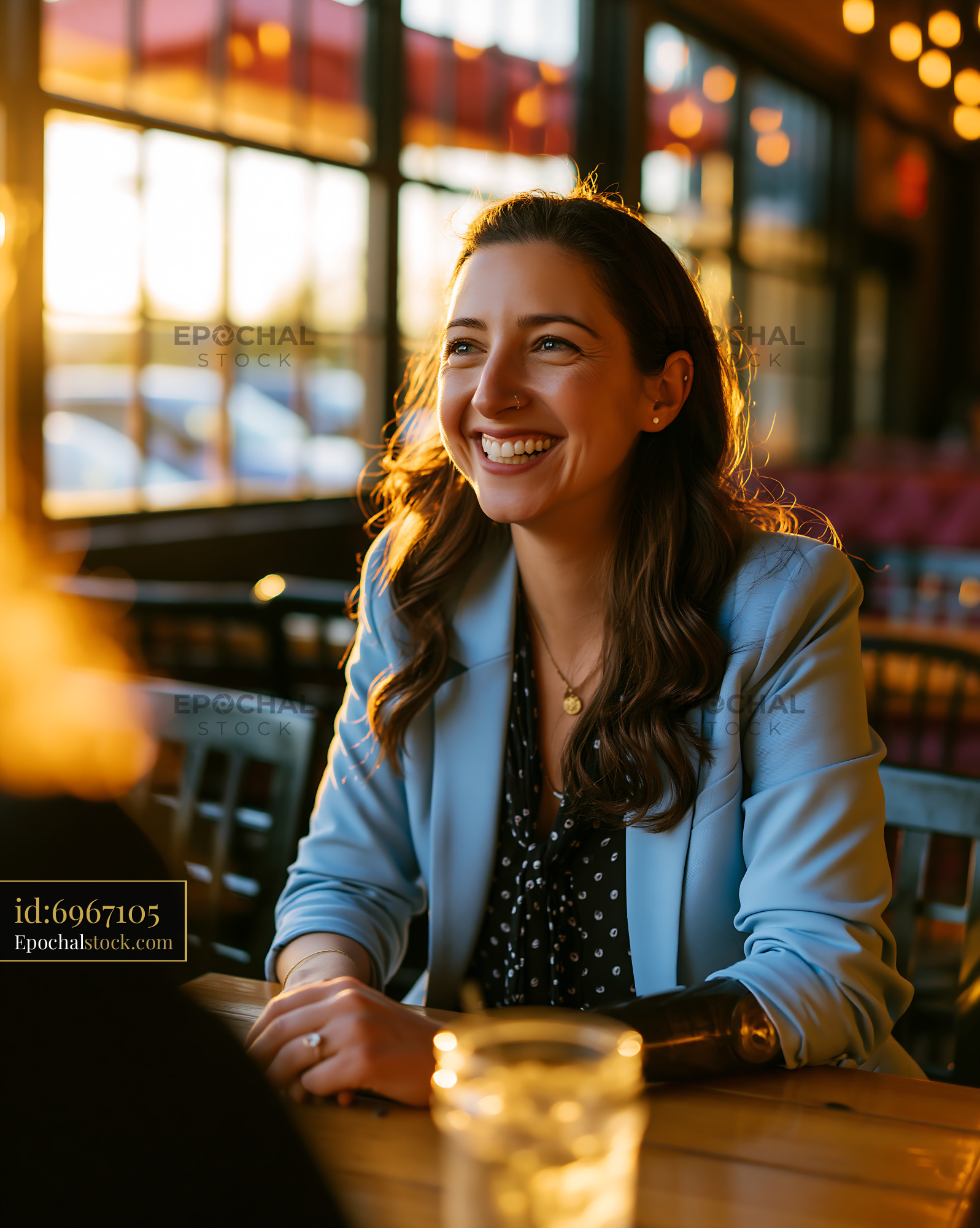 Watermarked full-resolution preview of Woman smiles at sunset in a restaurant, enjoying conversation
