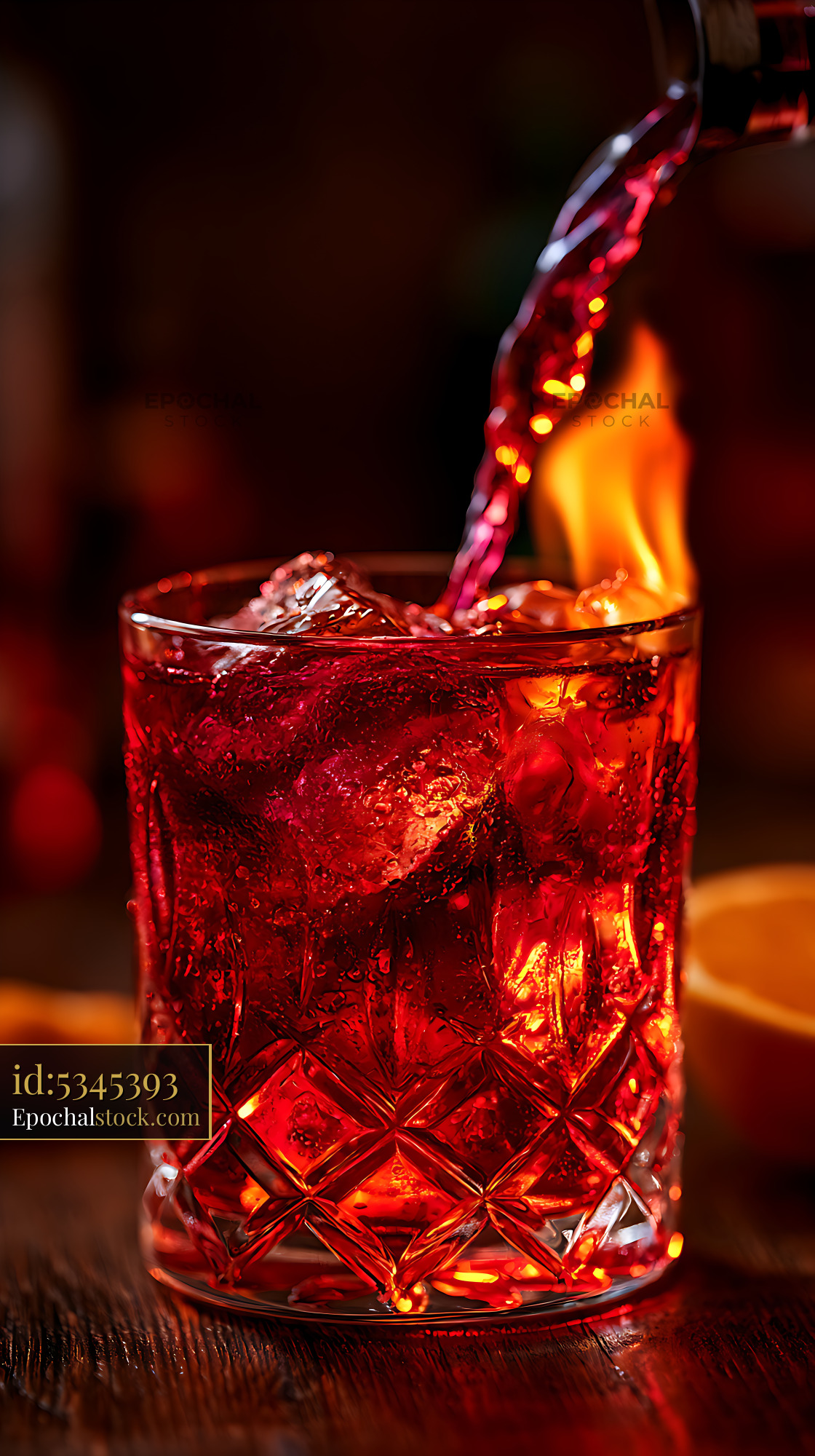 Watermarked full-resolution preview of Pouring a bright red drink into a glass with ice cubes