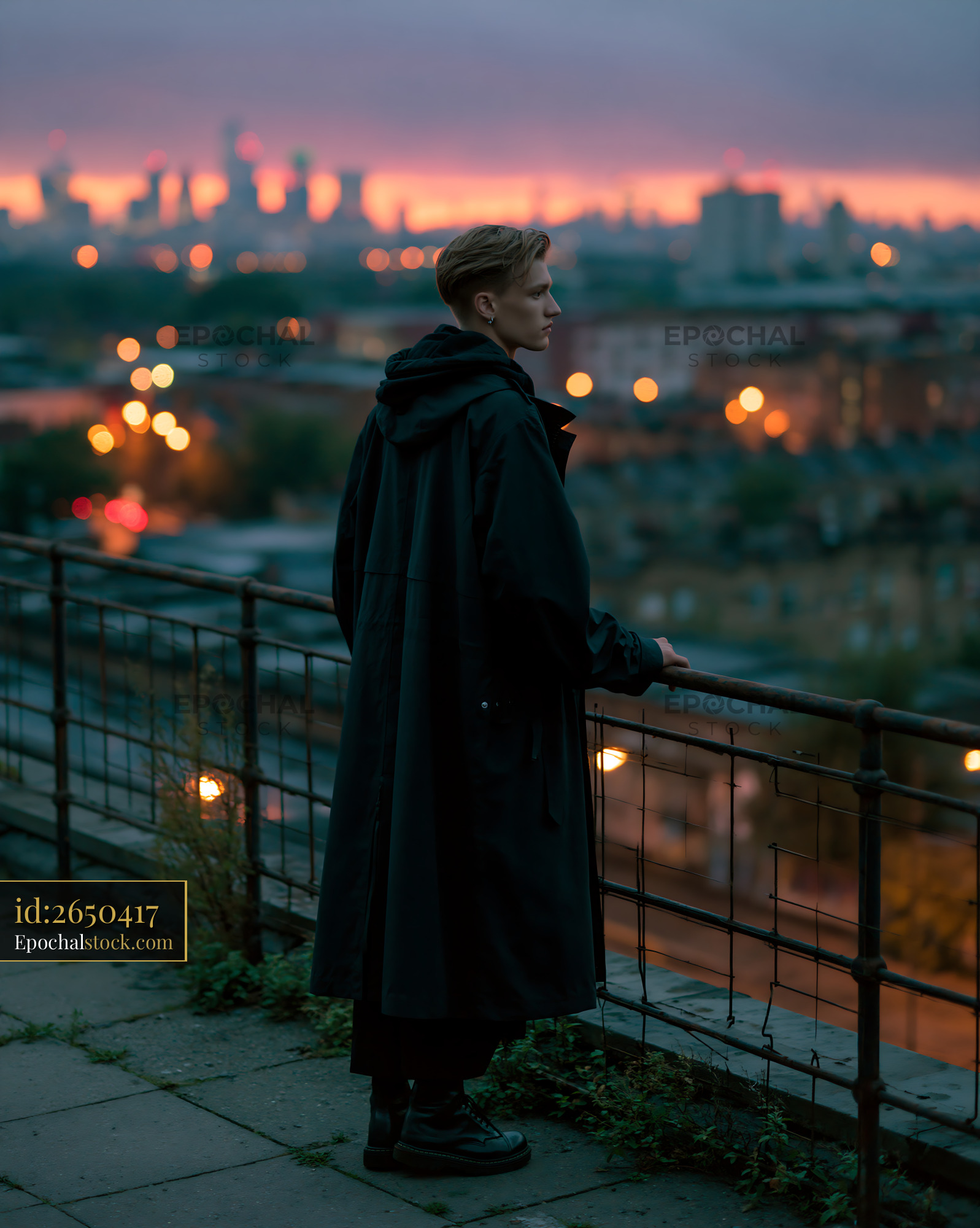 Watermarked full-resolution preview of Young person standing on rooftop railing during sunset in city