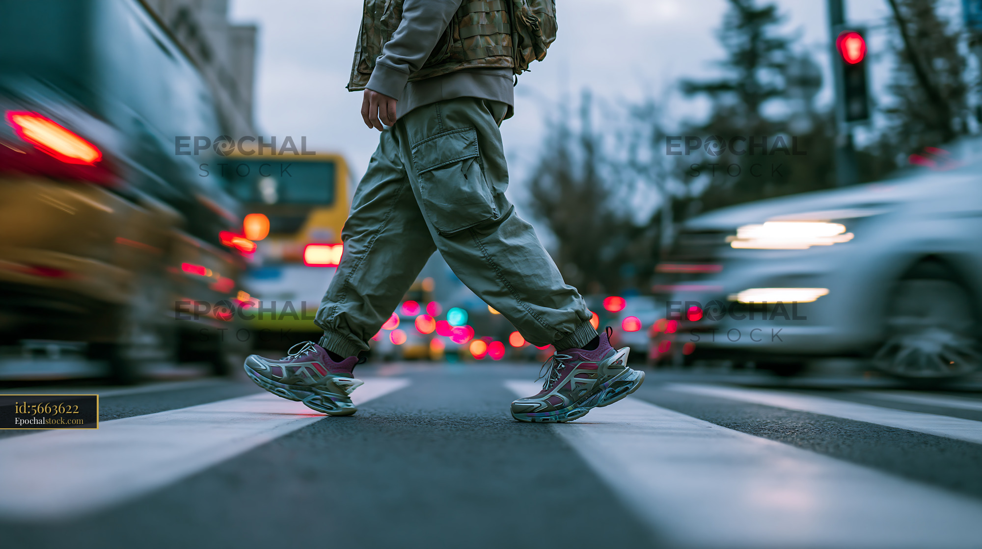 Watermarked full-resolution preview of Person crossing a street with moving vehicles in a city