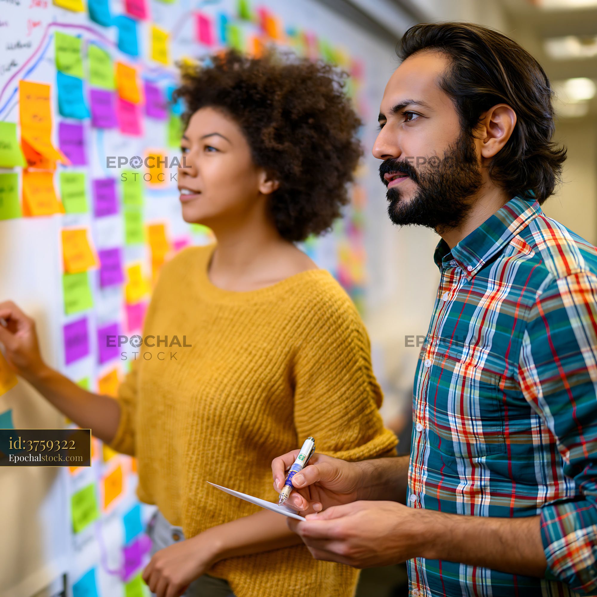 Watermarked full-resolution preview of Team members discussing ideas on a wall covered with sticky notes