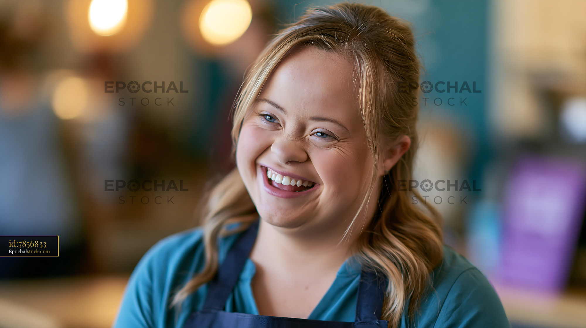Watermarked full-resolution preview of Smiling young woman in blue shirt and apron at a café