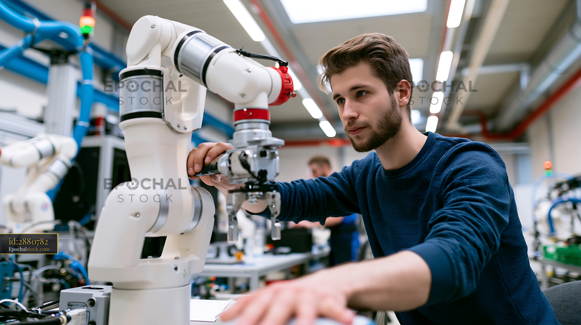 Employee Working With Robotic Arm in Modern Workshop