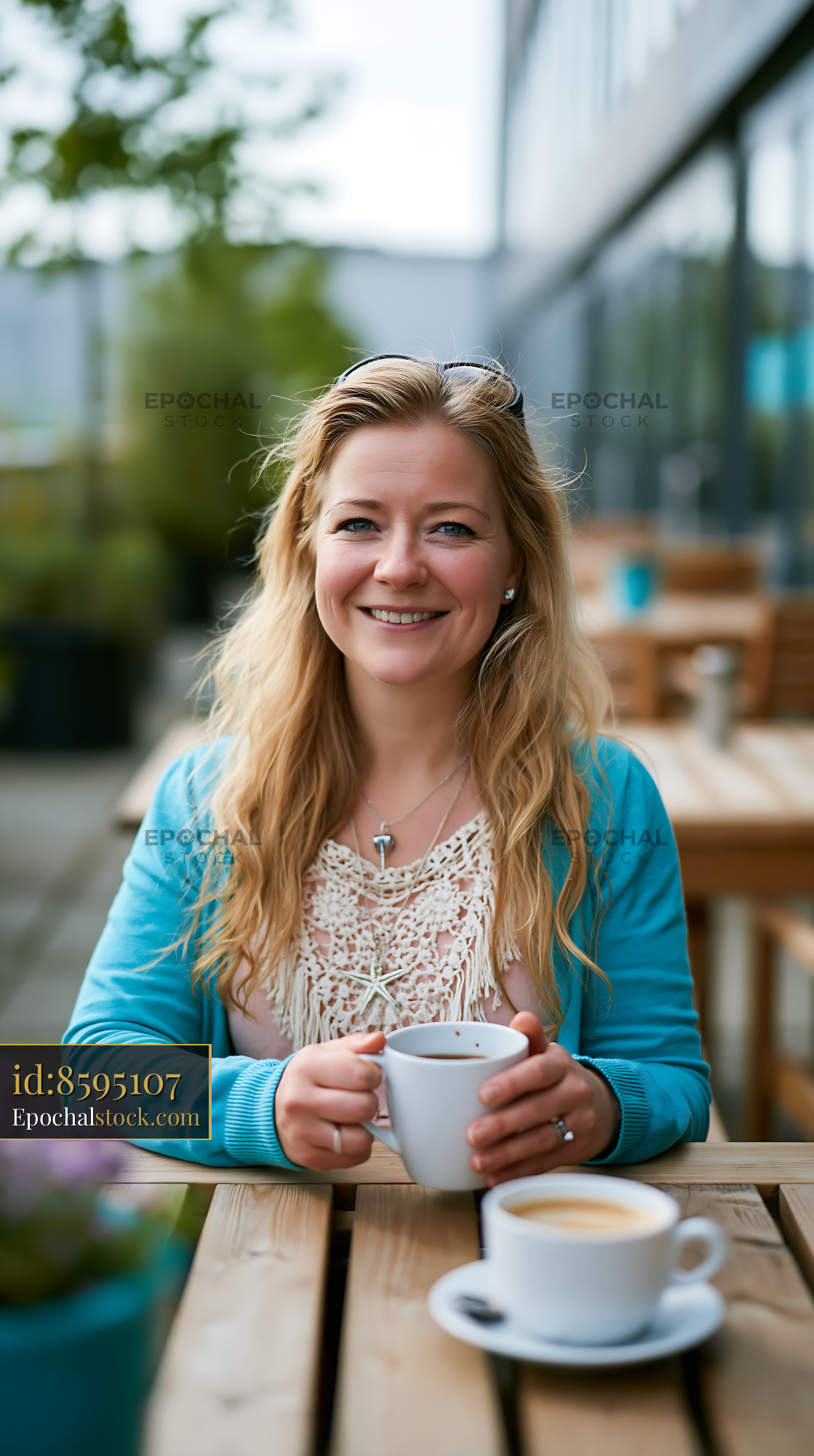 Watermarked full-resolution preview of Woman sitting at a cafe table holding a cup of coffee