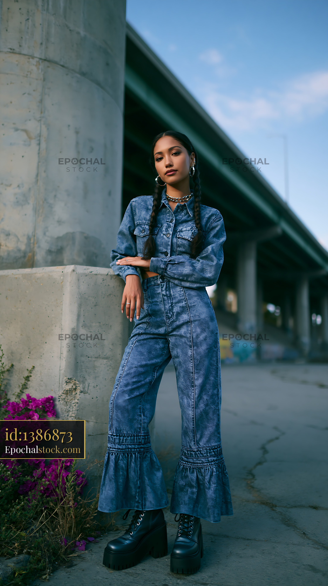 Watermarked full-resolution preview of Model poses in denim outfit near concrete structure with flowers