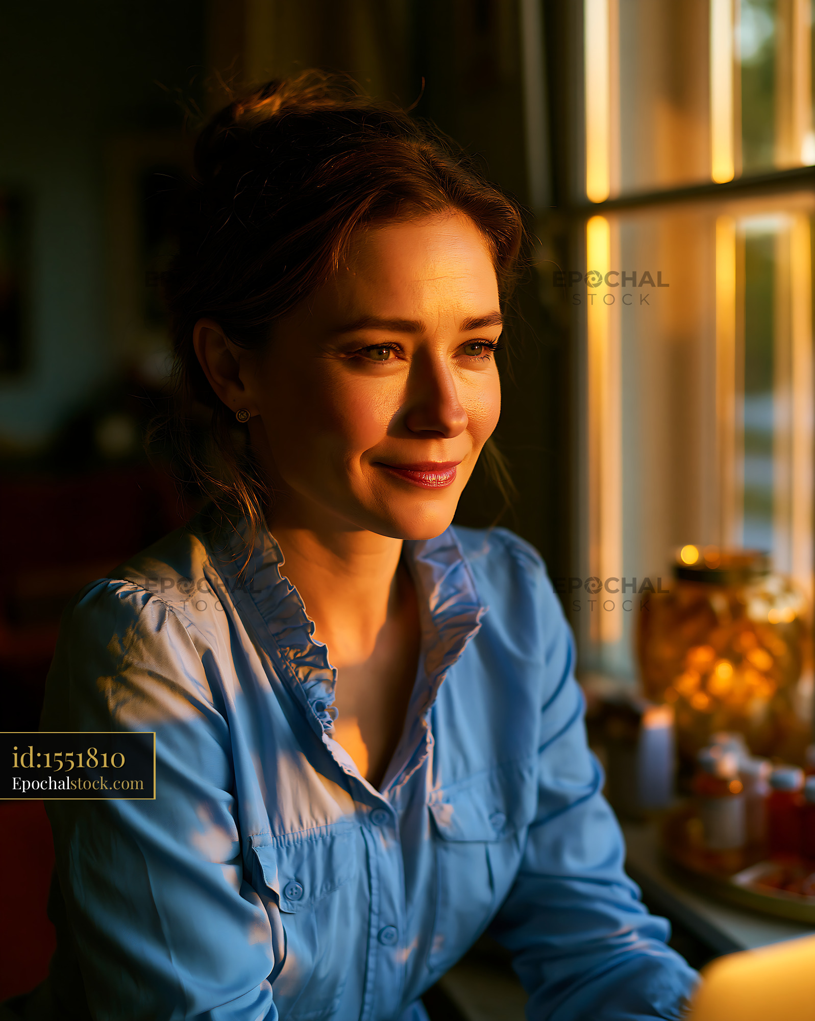 Woman in Blue Shirt Sitting by Window During Golden Hour - stock photo