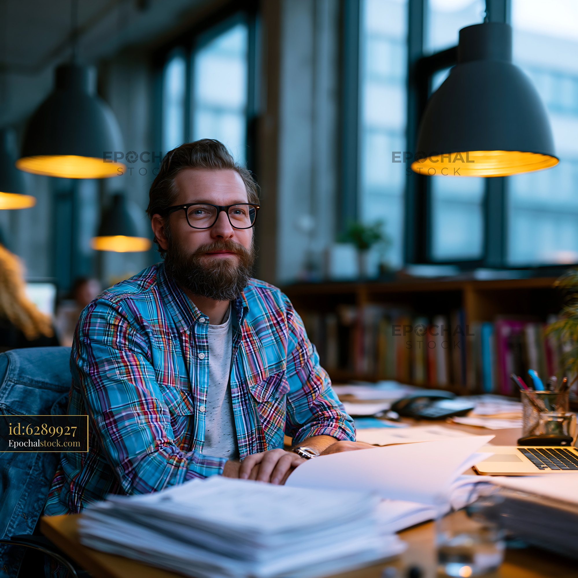 Watermarked full-resolution preview of Man working at desk in modern office during evening
