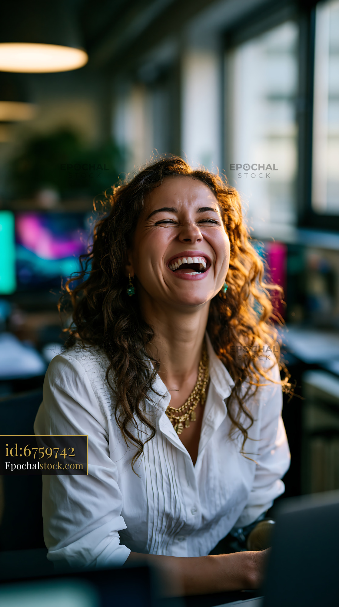 Watermarked full-resolution preview of Woman laughing while sitting in a bright office space