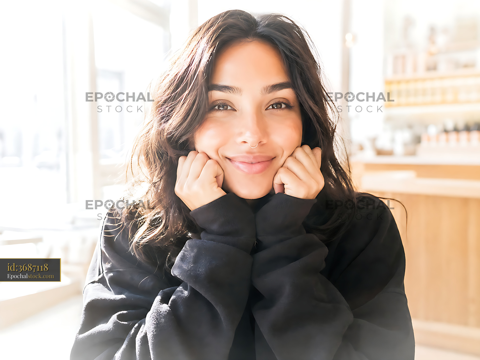 Watermarked full-resolution preview of Smiling woman sitting in bright cafe with hands on face