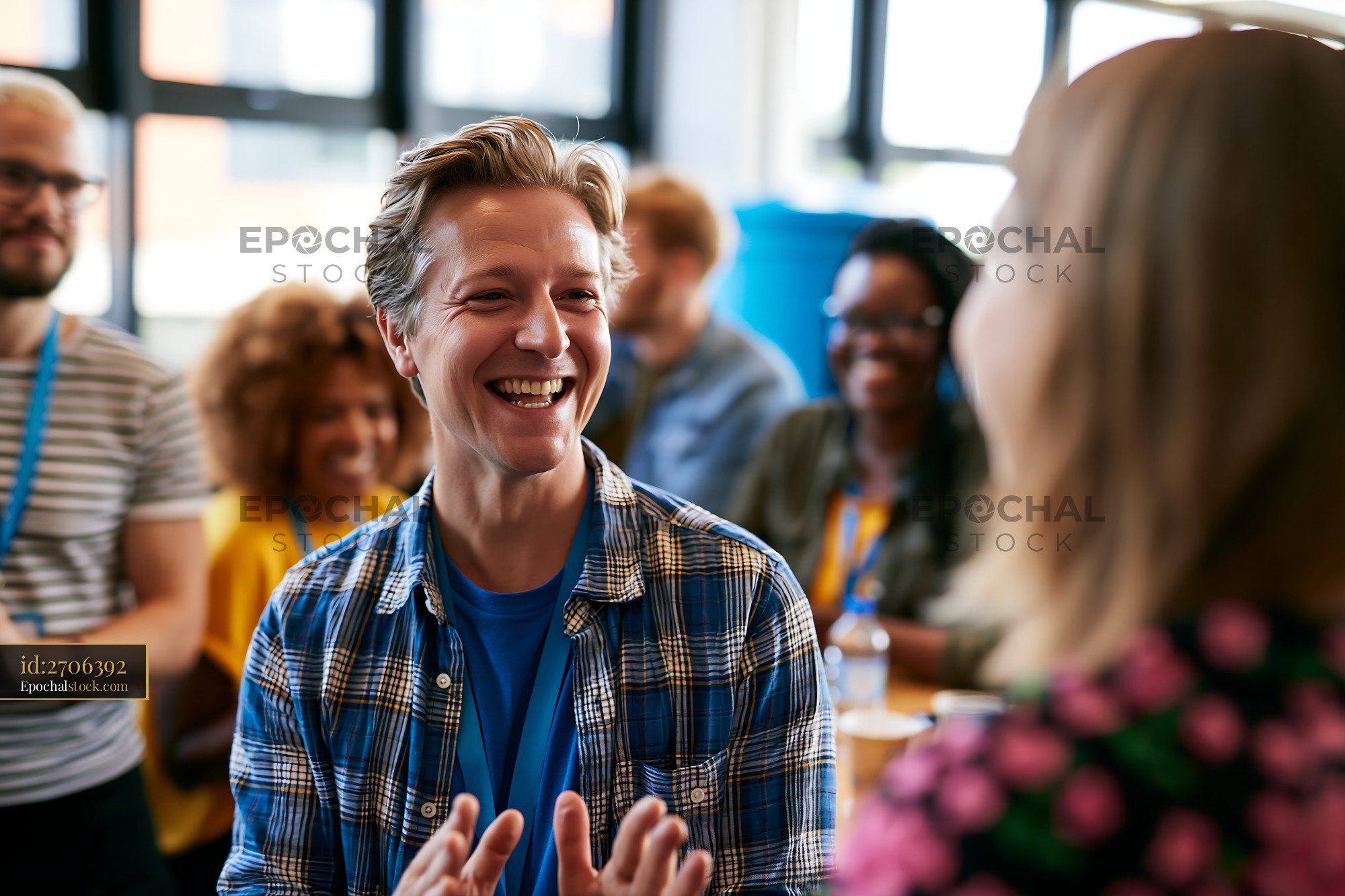 Watermarked full-resolution preview of Joyful man talking with people at an indoor social gathering