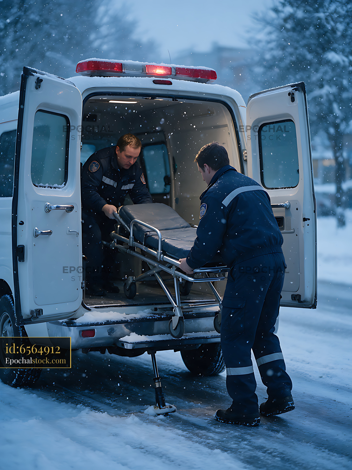 Watermarked full-resolution preview of Emergency responders load stretcher into ambulance during snowfall