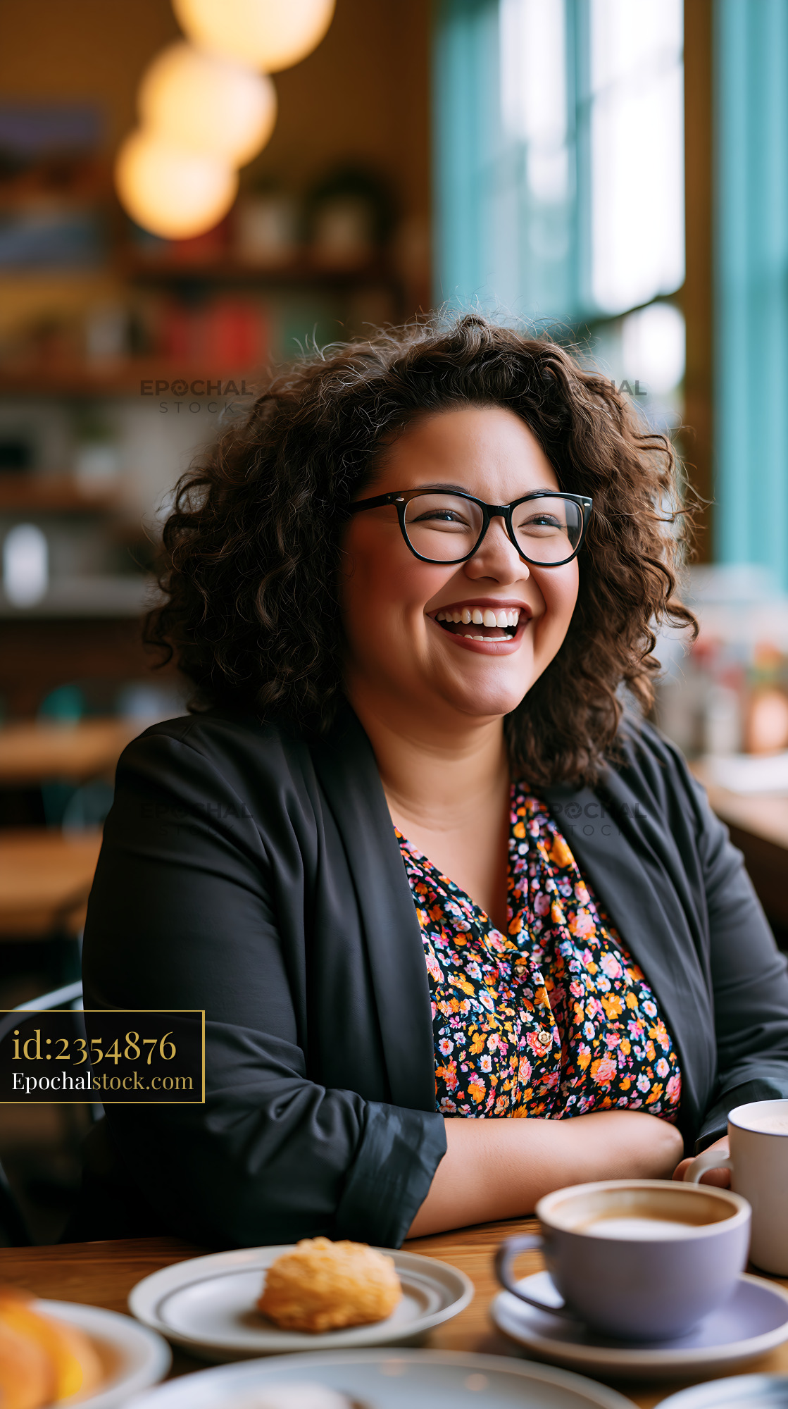 Watermarked full-resolution preview of Woman smiling in a cafe with curly hair and glasses, enjoying a drink