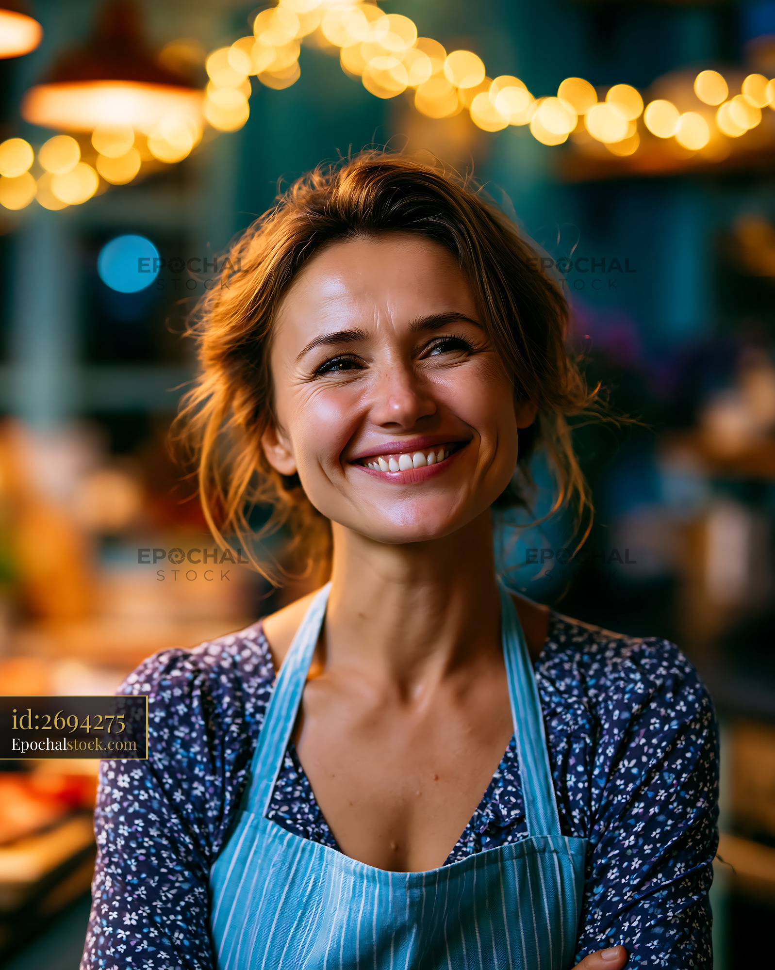 Watermarked full-resolution preview of Woman smiling in apron at cafe with warm lights