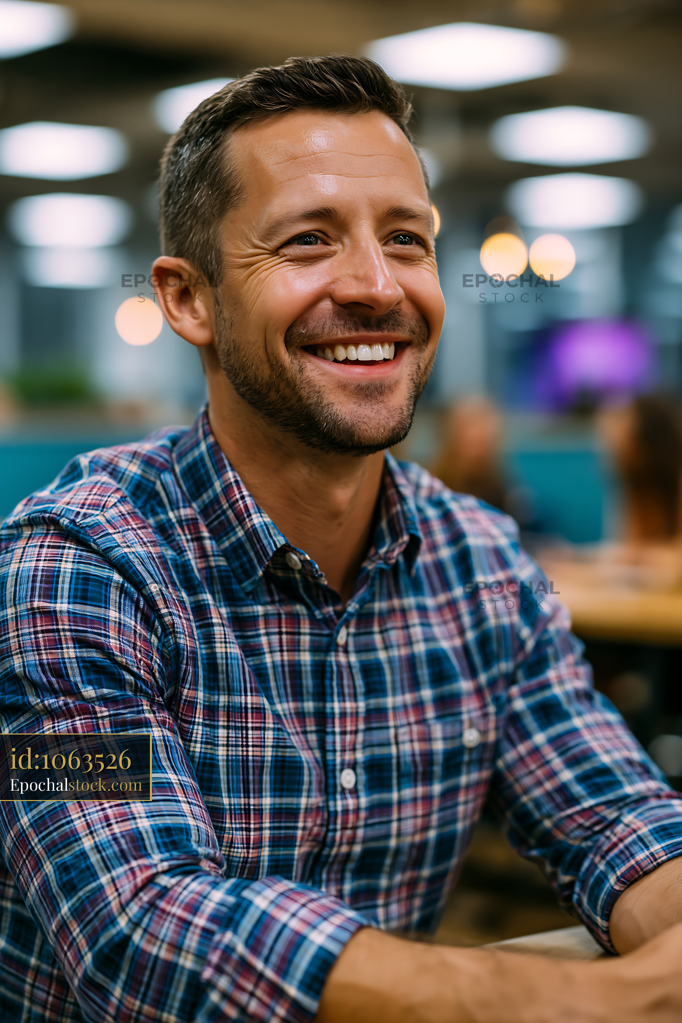 Man Smiling in a Checkered Shirt at a Casual Setting - stock photo