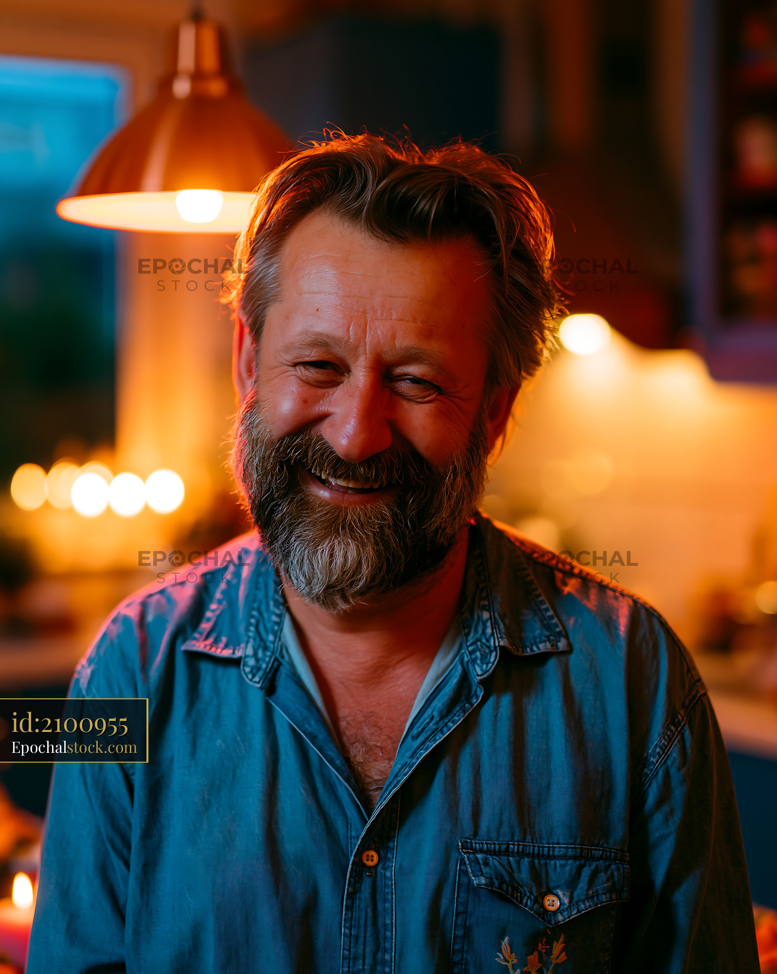 Man Smiles in Kitchen With Warm Light During Evening Gathering - stock photo