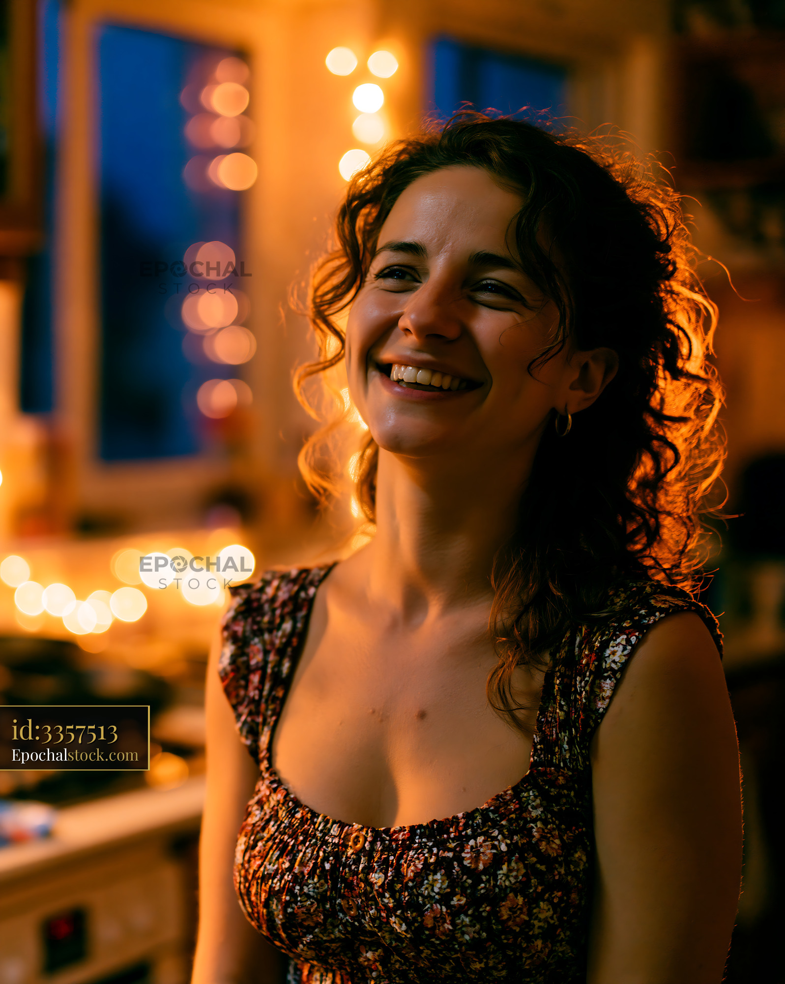 Woman Smiling in Cozy Kitchen at Night With Warm Lights - stock photo