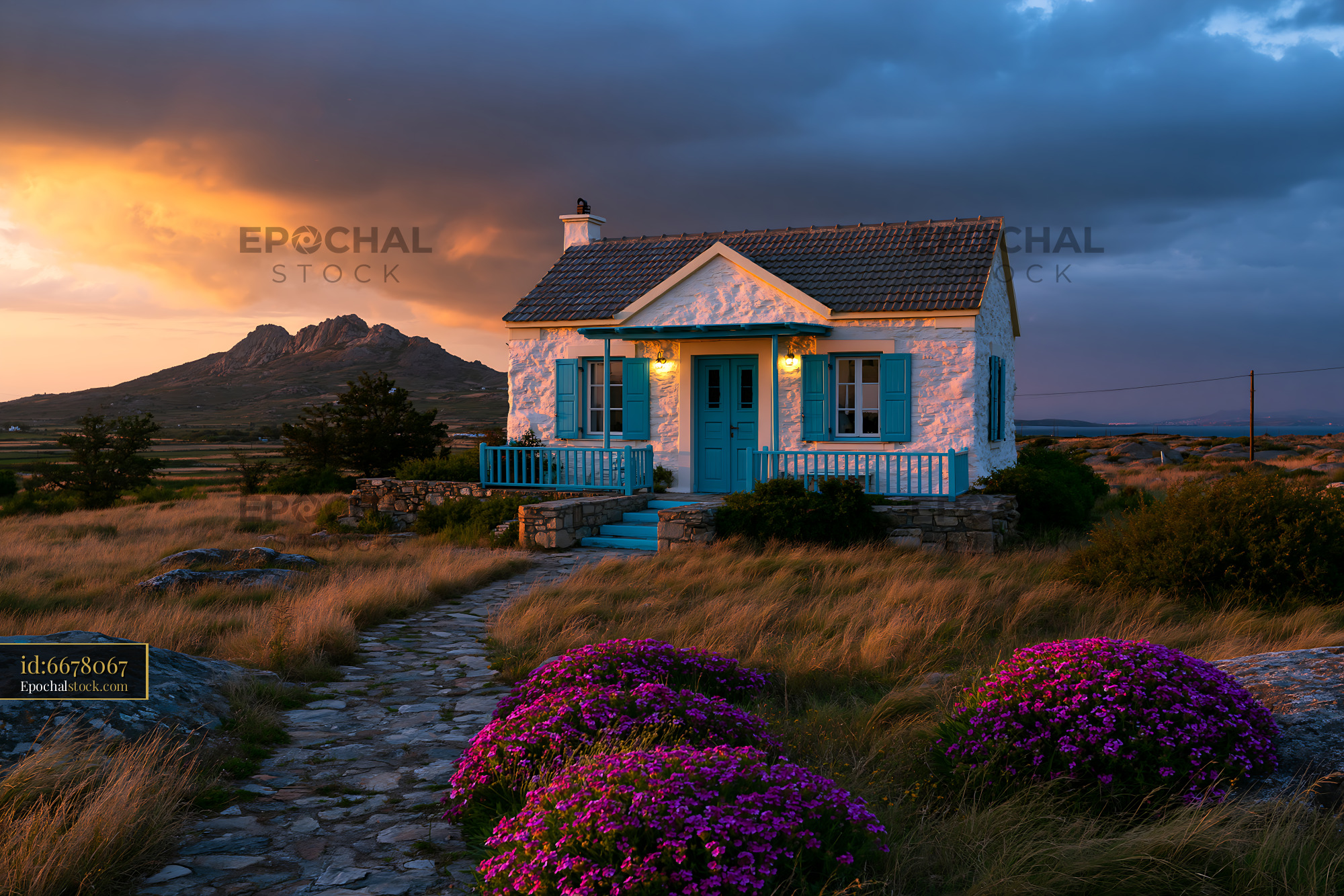 Stone cottage by the coast beneath a dramatic sunset sky