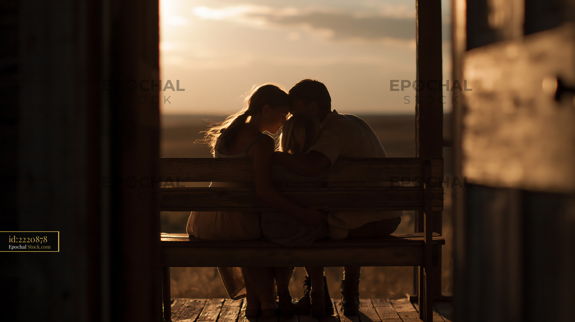 Young family sitting on a wooden bench at sunset - stock photo