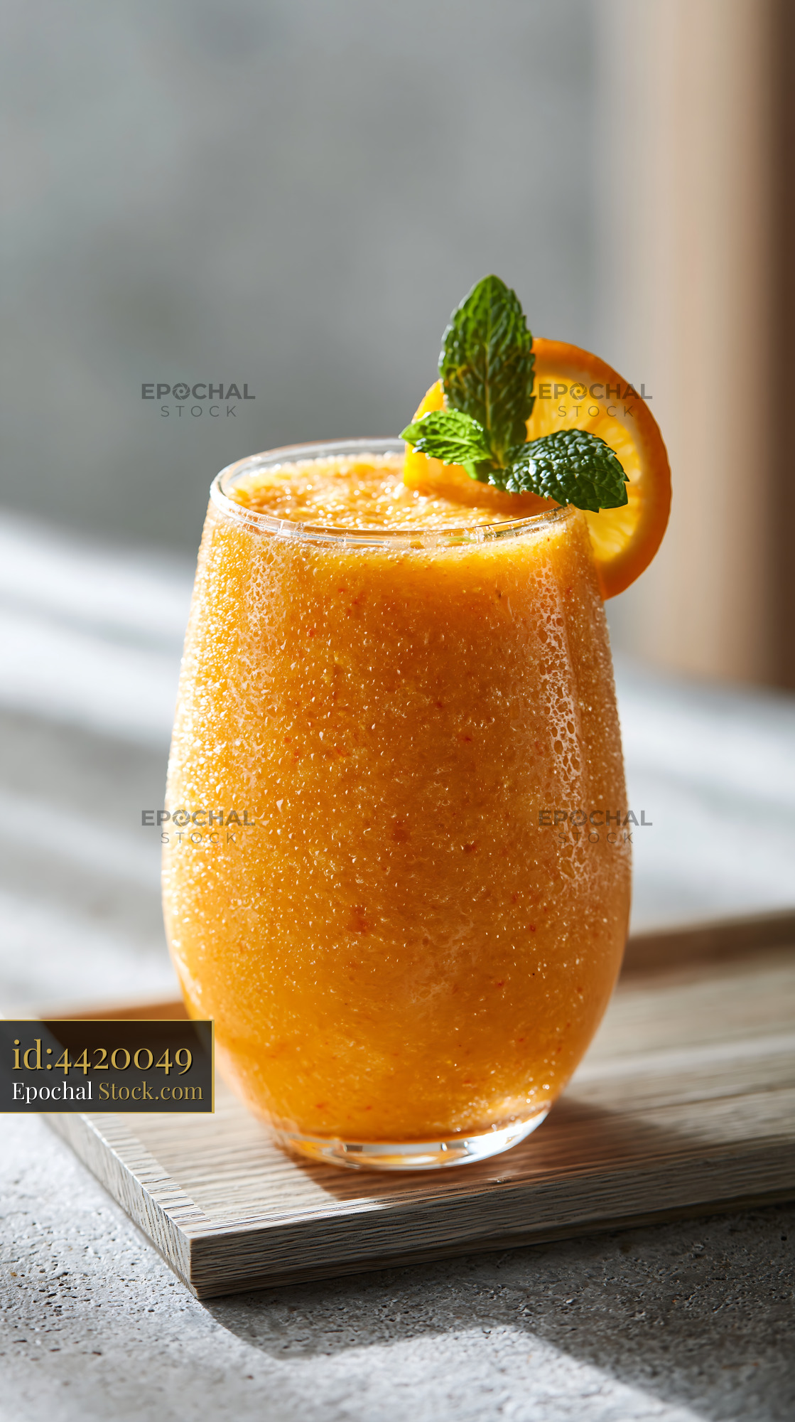 Mikan orange smoothie with mint garnish on a wooden tray - stock photo